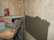 Нанесение плиточного клея перед укладкой плитки на стену